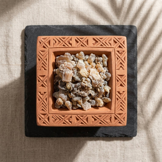 Terracotta dish with frankincense resin on a textured surface